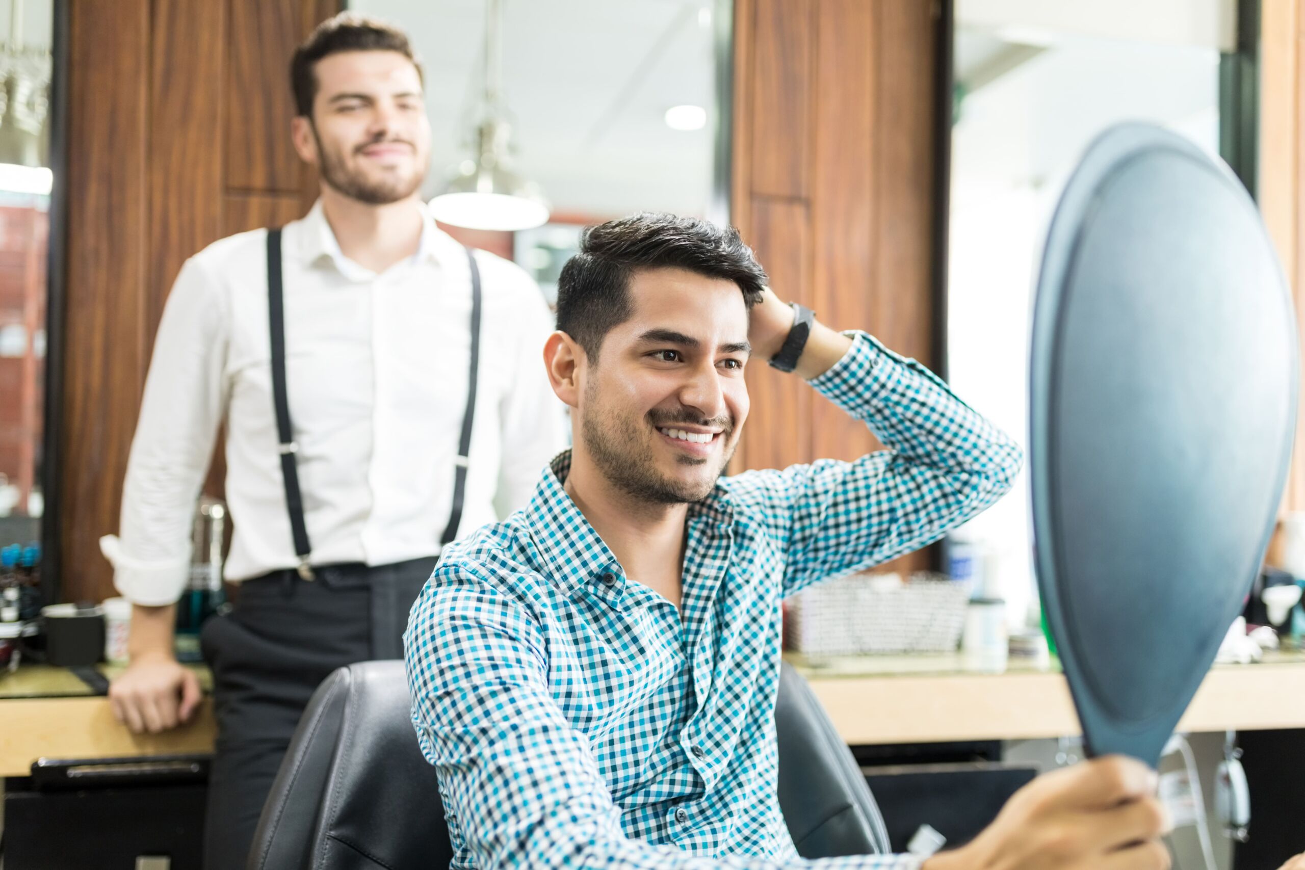 Man checking haircut in barbershop mirror.