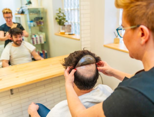Man receiving hairpiece fitting at salon.