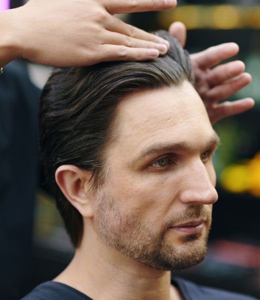 Man receiving hairstyling at a salon.